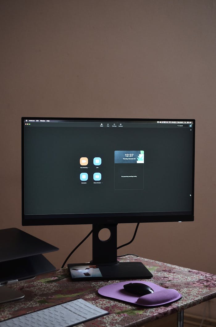A sleek desktop setup featuring a monitor, keyboard, and mouse on a patterned tablecloth.