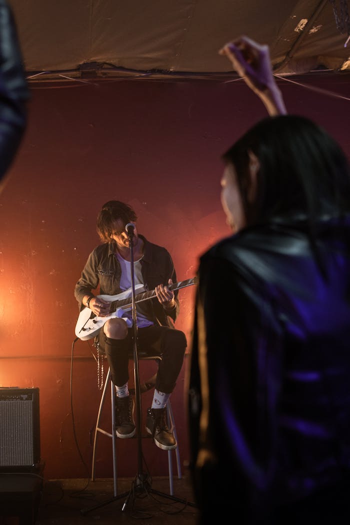 Guitarist playing on stage during a live performance with a spotlight.
